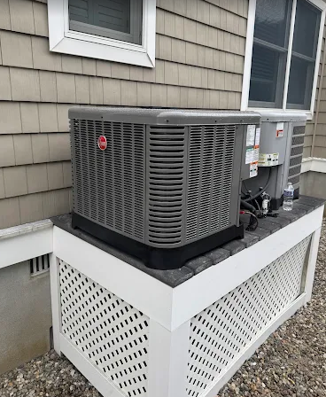 New Rheem central AC condenser installed on a raised platform